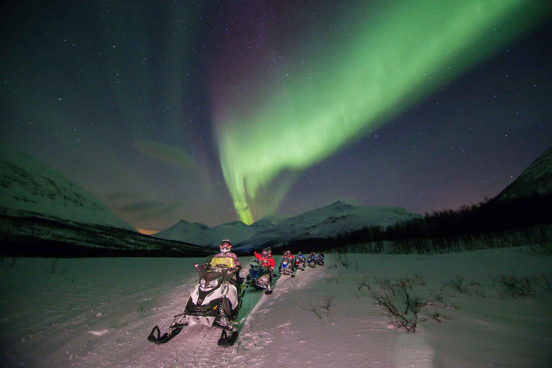 Photo. Group of people on Snowmobile safari under the northern lights